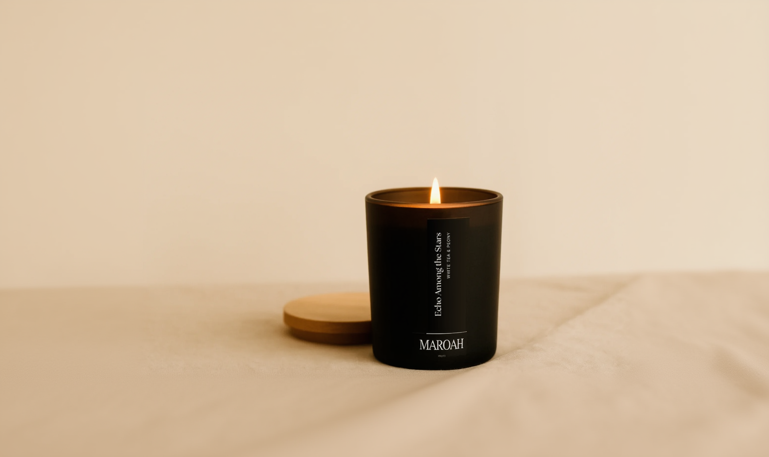 Black candle with Maroah logo on a beige background